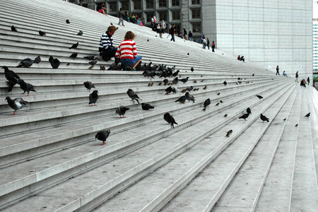 PARIS, FRANCE, AUGUST 18, 2006 - Two women feeding pigeons on the steps of the Grande Archeのeditorial素材
