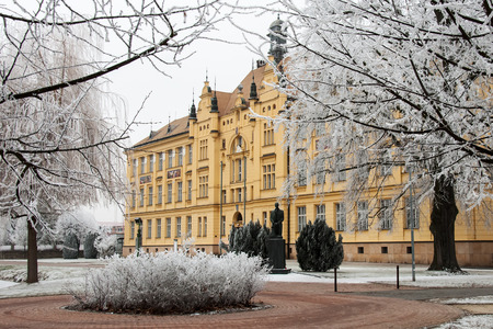 High school building in Litovel amongst hoar frosted trees in cold winter day, Czech Republic
