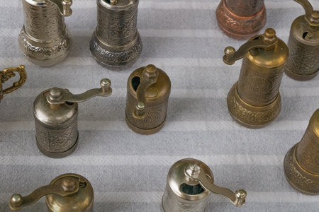 Collection of traditional metal coffee grinders with detailed engravings and patina finishes arranged on fabric, showcasing antique craftsmanship, rustic charm, and collectorâs appeal.の写真素材
