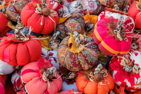 A cheerful collection of decorative fabric pumpkins arranged for display at a fall market. The mix of vibrant patterns, textures, and seasonal colors creates a festive harvest atmosphere.の写真素材