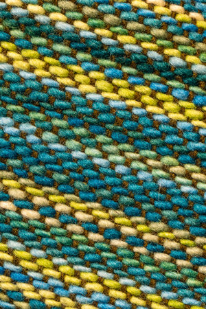 Macro view of woven textile fabric with multicolored threads forming a diagonal striped pattern,...