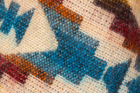 Macro close-up of traditional handwoven textile fabric showing colorful geometric pattern in blue,...