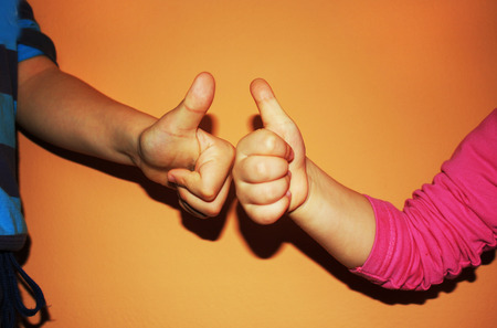 kids showing two thumbs up on orange backgroundの写真素材
