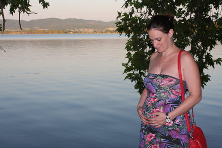 Young and pregnant woman relaxing next to the lake.の写真素材