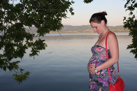 Young and pregnant woman relaxing next to the lake.の写真素材