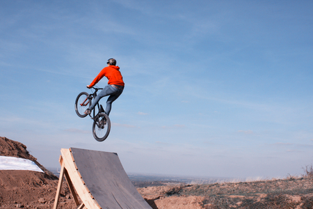 man in sportswear jumping high on mountain bicycle on background of landscape.の写真素材