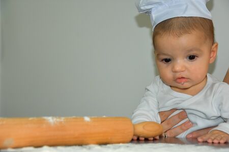 Cute baby boy cooking in kitchen at homeの写真素材