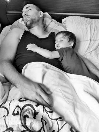 Father and son baby sleep tired on bed.の写真素材