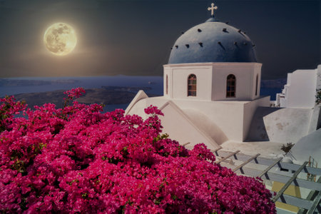 Santorini at night with blooming flowers and full moonの写真素材