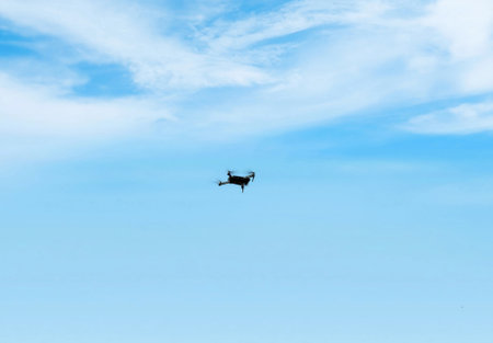Silhouette of a helicopter flying in the blue sky with cloudsの写真素材