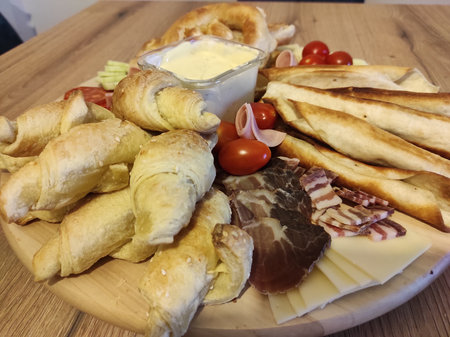 Breakfast with croissants, ham and cheese on a wooden tableの写真素材