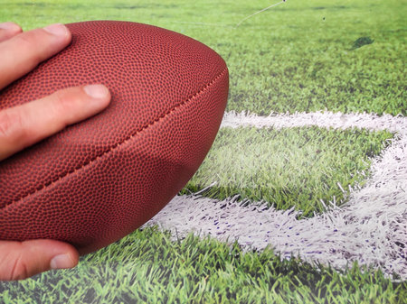 American football ball on the field with green grass and white line backgroundの写真素材