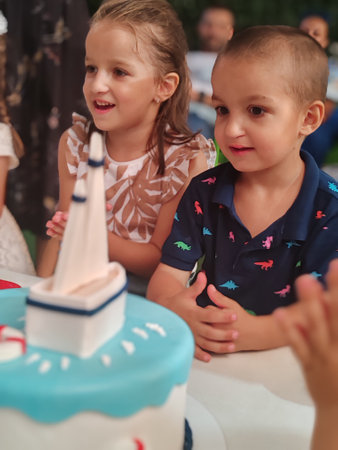 Cute little girls blowing out candles on a birthday cake at a birthday partyの写真素材