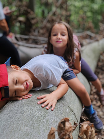 Boy and girl lying on a bench in the park with their eyes closedの写真素材