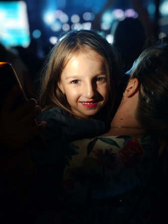 Happy girl and her mother take selfie with smartphone at Summer Music Festival