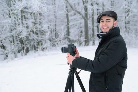 man in winter clothes with a camera on tripodの写真素材