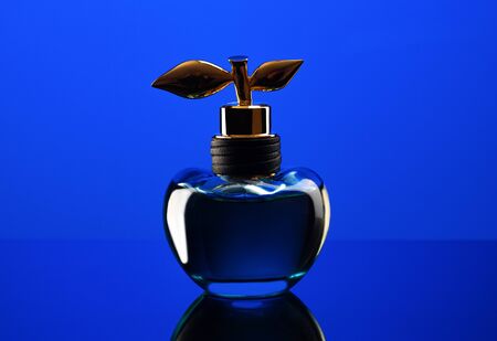 Bottle of expensive perfume shot close-up on a blue background