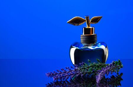 Bottle of expensive perfume shot close-up on a blue backgroundの写真素材