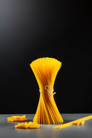 A bunch of raw Italian pasta shot in backlight against a dark backgroundの写真素材