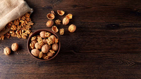 Walnut kernels and whole walnuts on a rustic old wooden table backlit