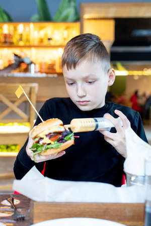 cute boy refilling a hamburger in a restaurant trying to eat itの写真素材