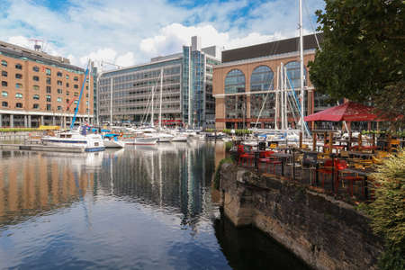 London, England -August 9th, 2018: Cafe by the water in St. Katharine Docks Marina, with view on anchored boats and buildings in the backgroundのeditorial素材