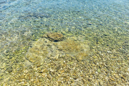 Magnificent, shallow sea at the shore of Rogoznica, small fishing town in central Dalmatia, Croatia, with stones and rocks underneath clear water surfaceの写真素材