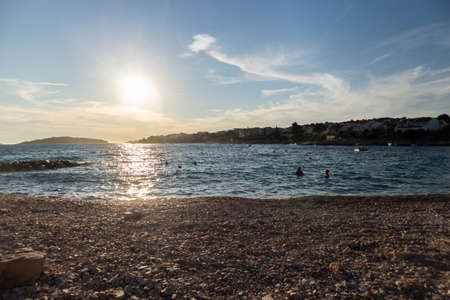 Beautiful summer sunset over small town of Rogoznica, with open Adriatic sea splashing the rocky shoreの写真素材