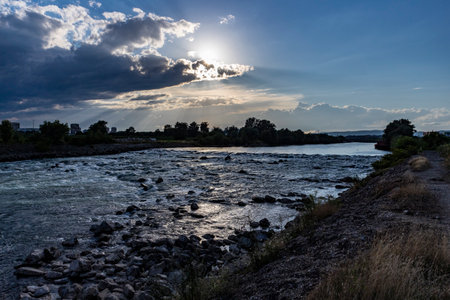 Beautiful sunset over Sava river rapids in Zagreb city, with storm clouds approaching fast, bringing heavy rainの写真素材