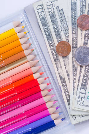 Box of color pencils with paper and coin money