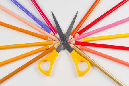 Yellow scissors surrounded by the pencils of warm colorsの写真素材