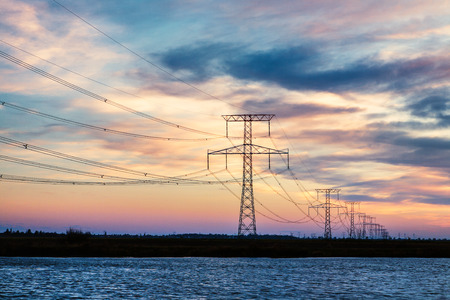 High voltage power lines over Little Danube river, Slovakia at sunset. Environmental or energy distribution concept.の写真素材