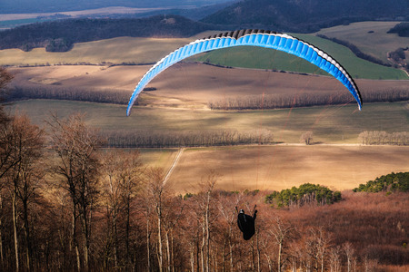 Paragliding take off from Male Karpaty mountains with late winter landscape in background. Outdoor and adventure sports lifestyle theme.の写真素材