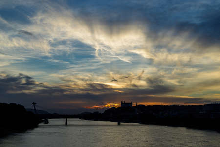 Sunset over Danube river with silhouettes of castle and SNP bridge, known landmarks in Bratislava, capital of Slovakiaのeditorial素材