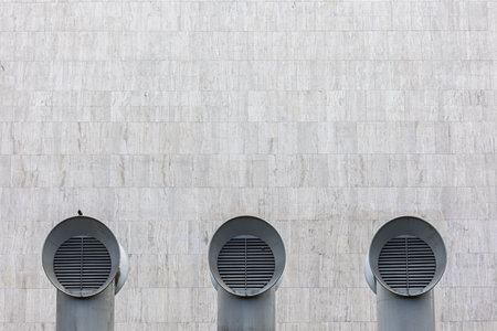 Symmetrical ventilation shafts with travertine wall in background in Bratislava, Slovakia. Minimalistic composition.の写真素材