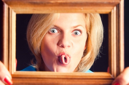 The girl in a blue dress against a dark background puts out the tongue の写真素材