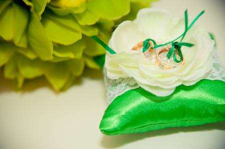 wedding rings lie on a green cushion for ringsの写真素材