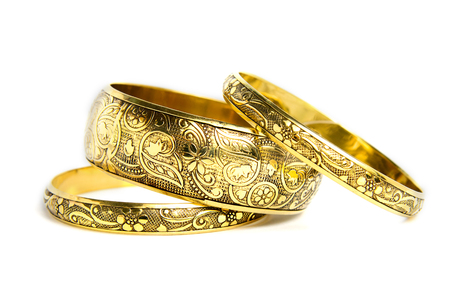 Three golden bracelets on a white backgroundの写真素材