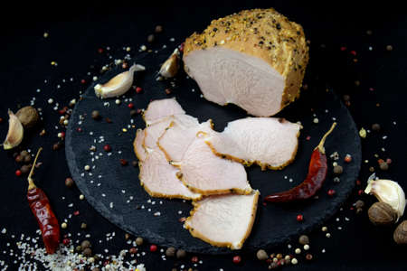 Appetizing sausage sliced on a slate board on a black background with spices and chilli, selective artistic focusの写真素材