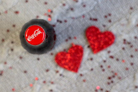 LVIV, UKRAINE - DECEMBER 19, 2020: Coca Cola glass bottle red cap, on red blured background selected...