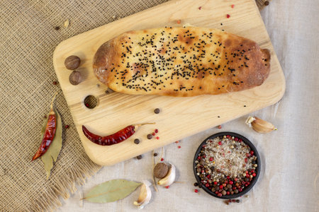 Appetizing baked cake with black sesame seeds and spices on rough linen background close up