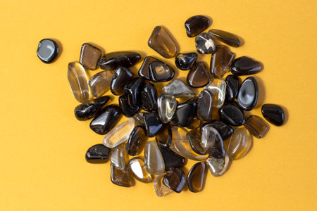 Macro shooting of collection natural rock set of morion, smoky quartz gem mineral stones on yellow...