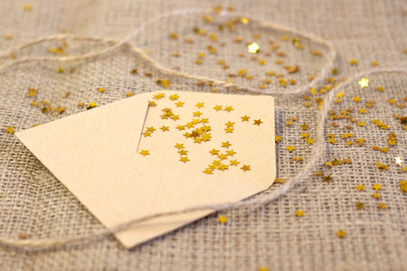 Cute craft paper envelope, scattered golden stars close up on gray linen Narrow focus line, shallow depth of fieldの写真素材