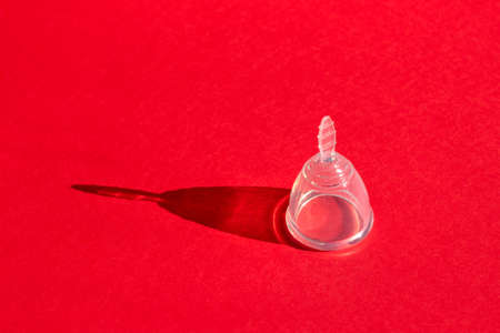 Feminine hygiene product, menstrual cup concept on bright red background with concept shadow