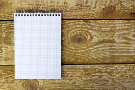 White spring notepad with blank space for writing on brown wooden textured background top viewの写真素材