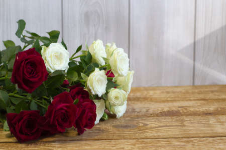 Bright burgundy and colored flowers in a bouquet on light wooden background close-up front viewの写真素材