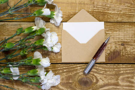 Simple small envelope with space for writing and cute small rose on wooden background with a pen close-up Narrow focus line, shallow depth of field high angle viewの写真素材