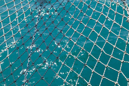 Bright blue background with maritime fishing net and blurred sea waves Close upの写真素材