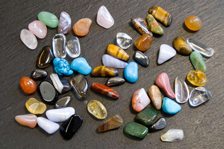 Collection Of Semi-Precious Gemstones on black slate blackboard background close up top view