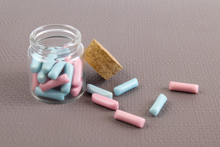 Jar full of blue and pink candies against soft gray background close up